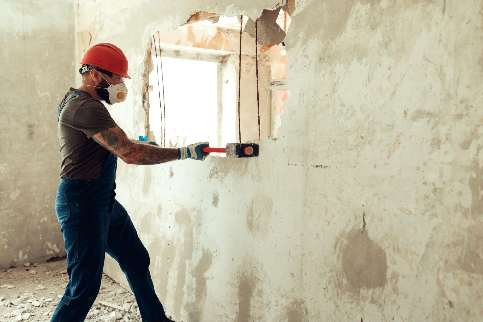 A handyman removing a wall with a sledgehammer