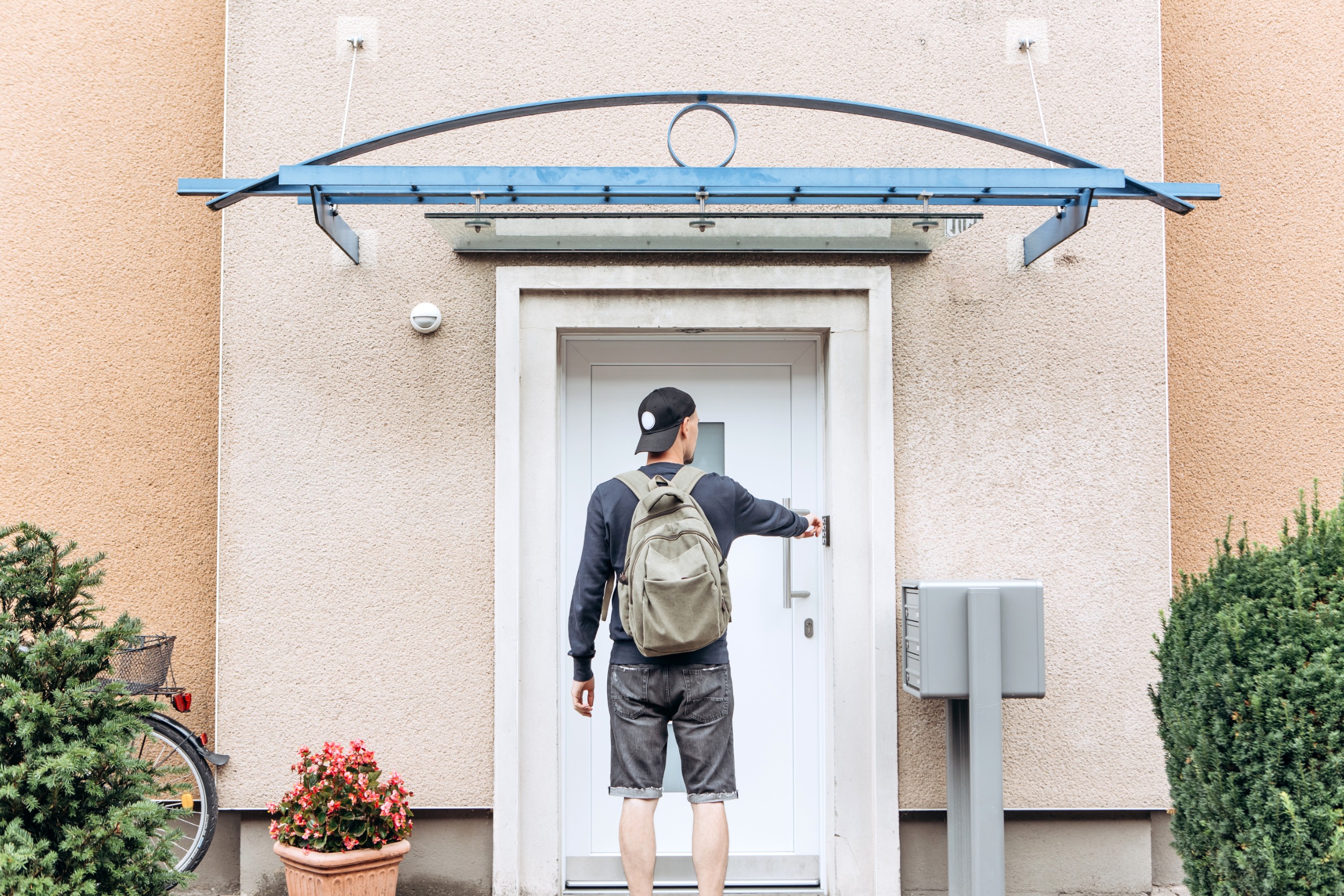 Young man with backpack ringing a doorbell